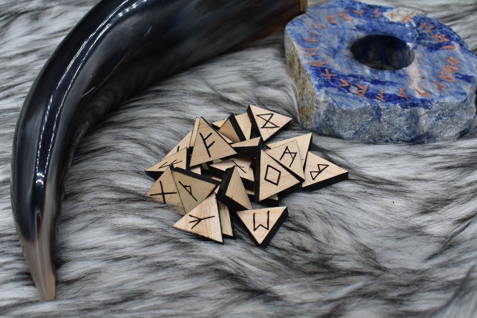 decorative photo of laser cut triangle ash runes on an altar with Viking drinking horn and sodalite candle holder