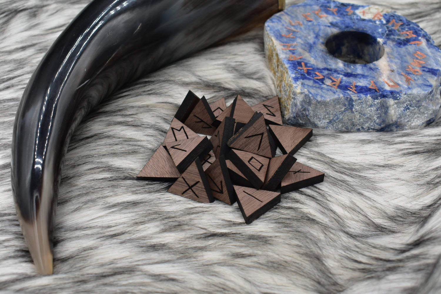 decorative photo of laser cut triangle walnut runes on an altar with Viking drinking horn and sodalite candle holder
