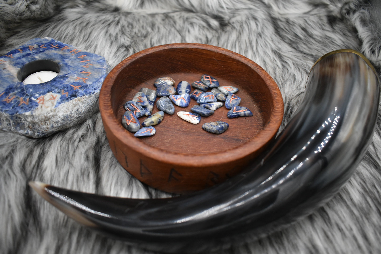 decorative photo of mini sodalite elder futhark runes in a bowl on an altar with Viking drinking horn and sodalite candle holder