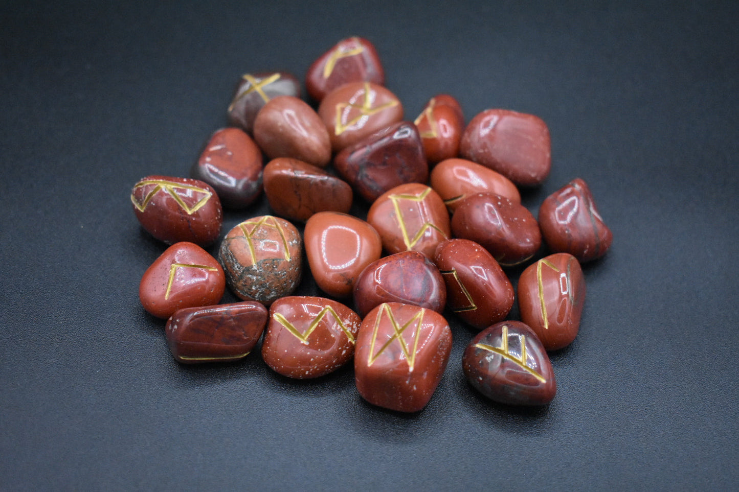 Product photo of red jasper elder futhark runes with gold inlay