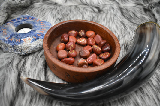 decorative photo of jasper elder futhark runes in a bowl on an altar with Viking drinking horn and sodalite candle holder