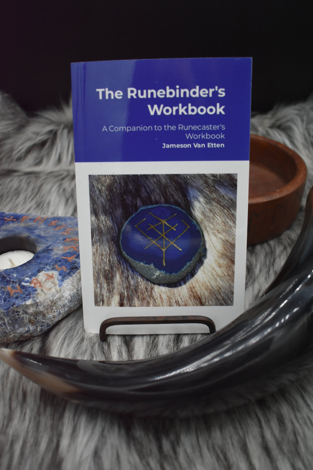 Decorative picture of the runebinder's workbook on an altar with a Viking drinking horn and sodalite candle holder