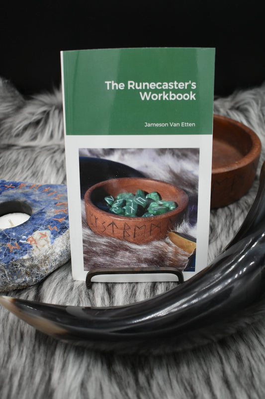 Decorative picture of the runecaster's workbook on an altar with a Viking drinking horn and sodalite candle holder